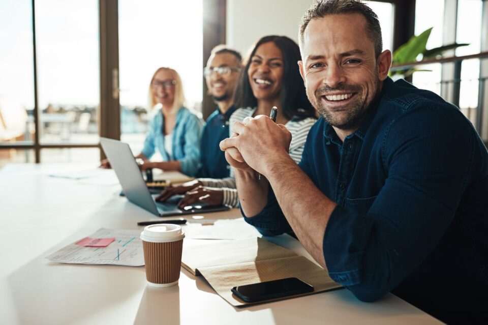 Office workers sitting at a table and smiling