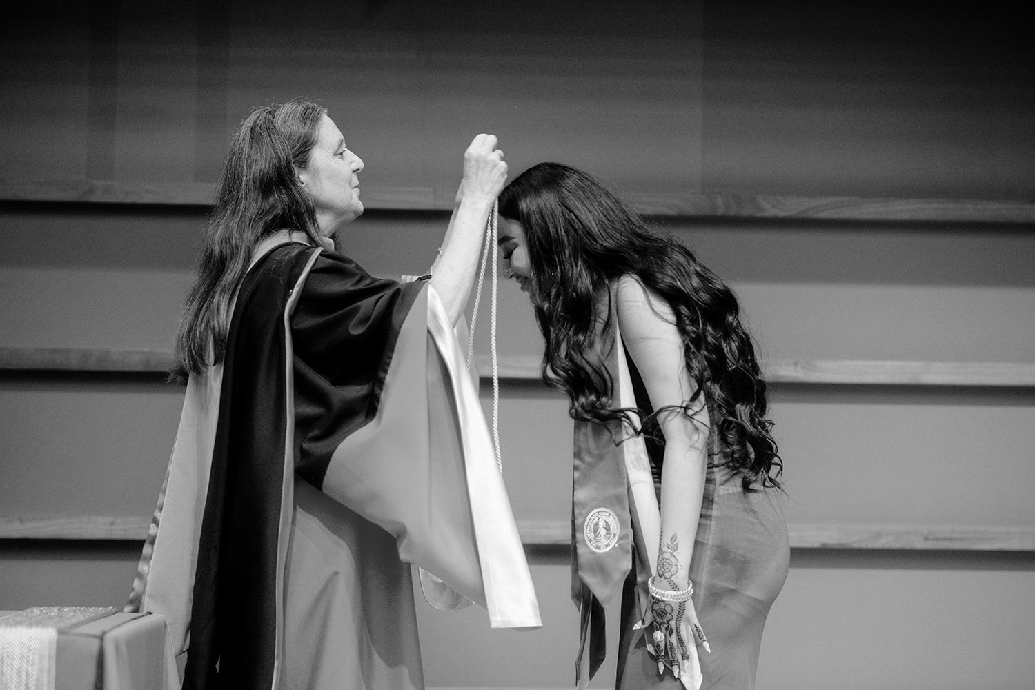 Image of Jennifer Wolf bestowing honors on a graduating students during the ceremony.