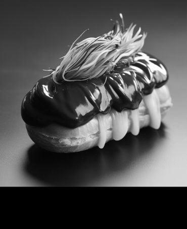 AI-generated image showing a chocolate éclair with a candyfloss topping styled to look like hair.