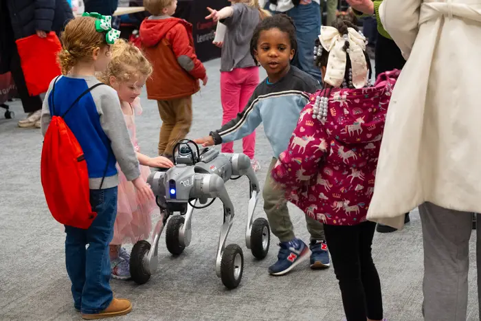 Children interact with a four-wheeled robot at the RIC.