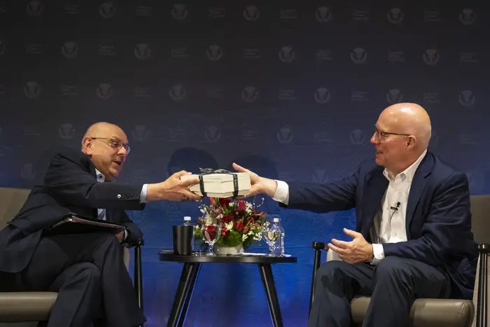 Farnam Jahanian hands Ted Decker a stack of books.