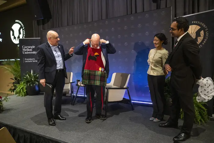 Ted Decker dons an apron designed with a CMU Scotty onstage with three others.