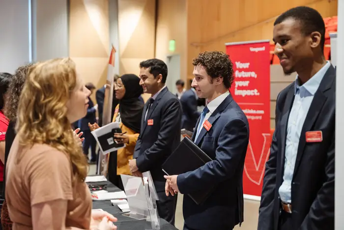 Students stand at various booths during a career fair.