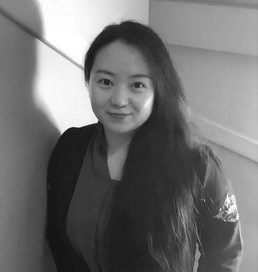 Portrait photo of Dr Yige Sun, a young woman of Asian descent with long black hair wearing a black jacket and turquoise top.