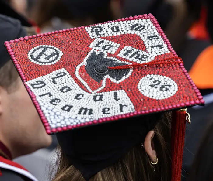 A student's graduation cap reads: Power to the local dreamer.