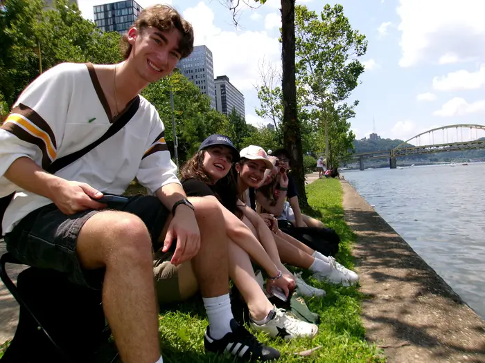 Students sit by the river.