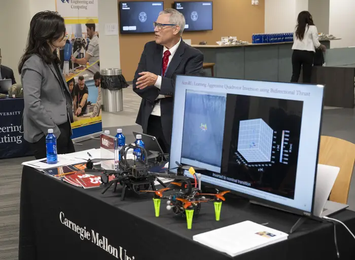 Wennie Tabib, left, who leads the Resilient Intelligence Systems Lab at CMU’s Robotics Institute, talks with Thomas Longstaff